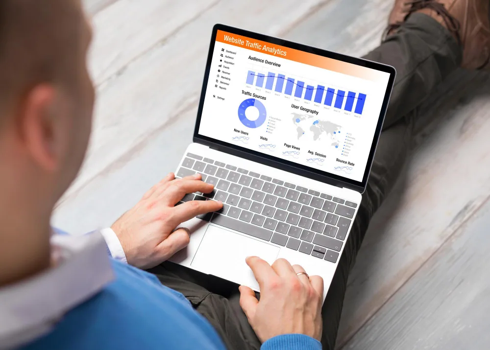 Business professional analyzing website analytics data on a computer screen with charts and graphs.